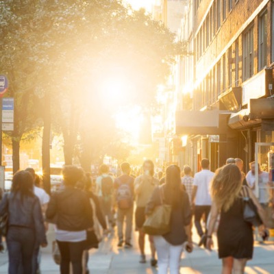 people walking in the street with a glowing sun